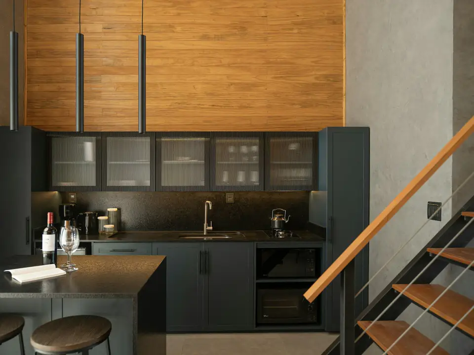 Cocina moderna con mesada oscura y revestimiento de madera
