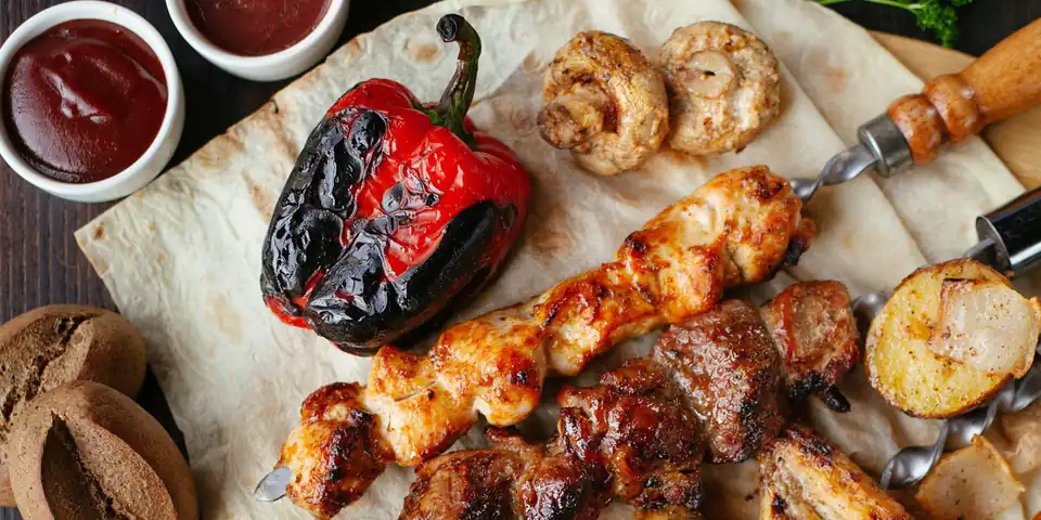 Parrillada completa con chorizos, pollo, verduras asadas y salsas