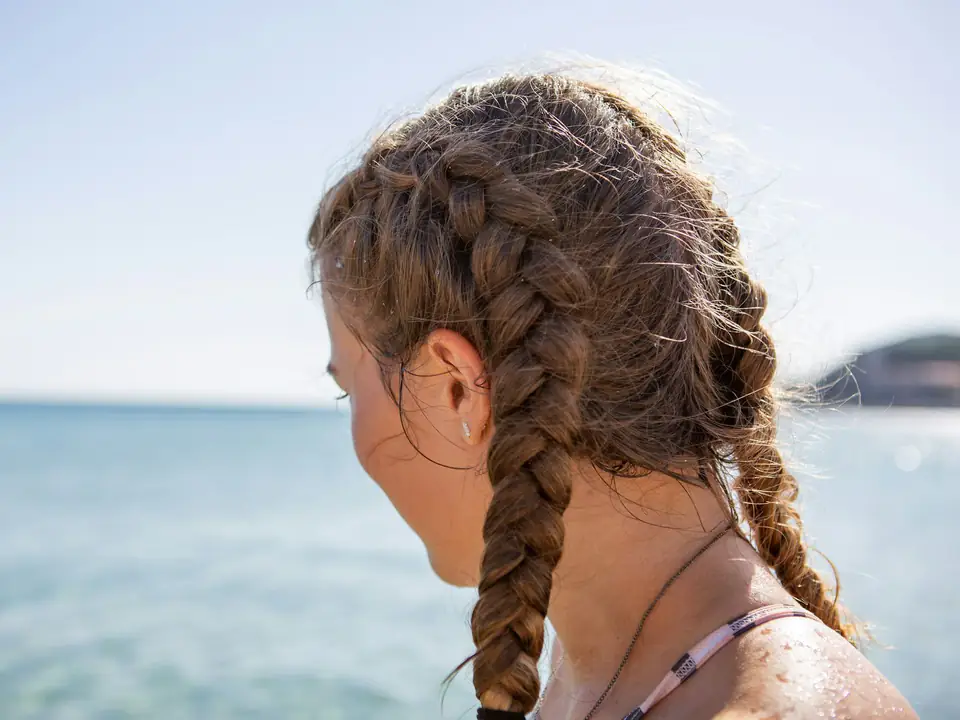 Una chica con dos trenzas mira el mar