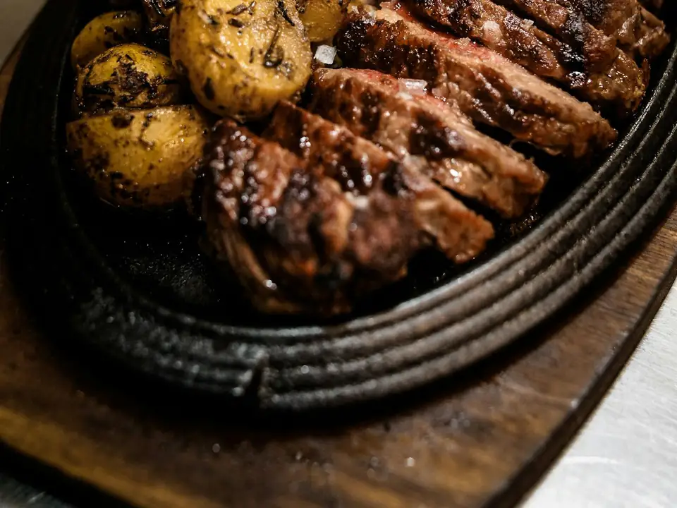 Vacío en fetas con papas asadas en una fuente de hierro