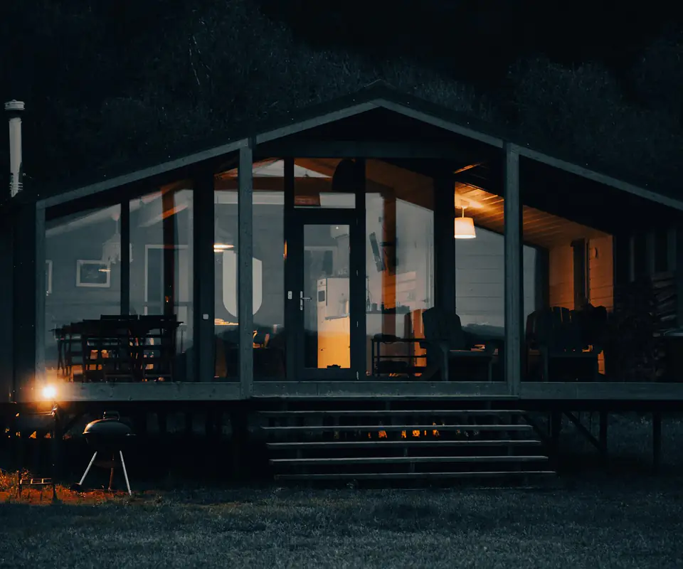 La cabaña de noche, con los ventanales encendidos