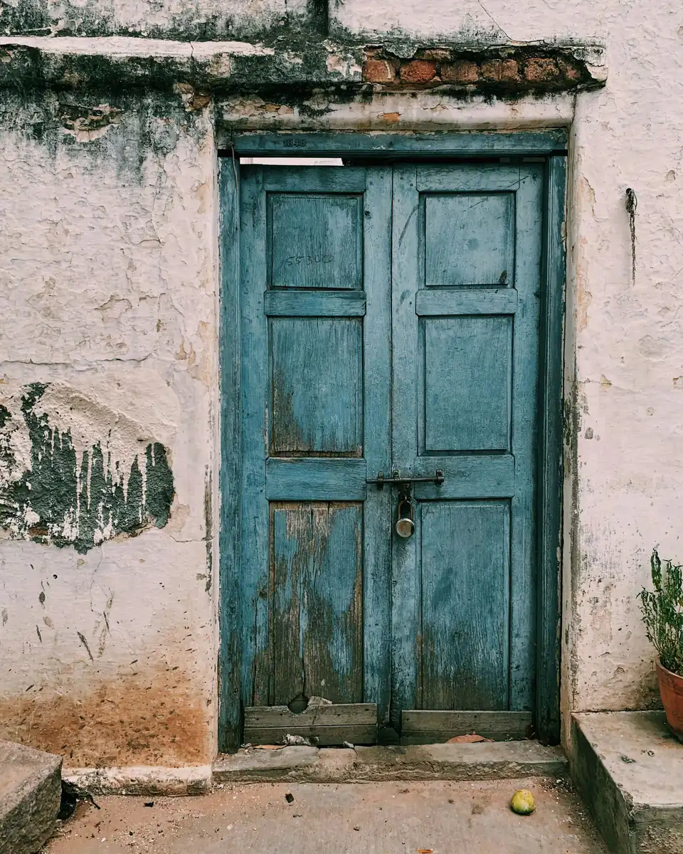 Puerta doble de madera con la pintura celeste descascarada
