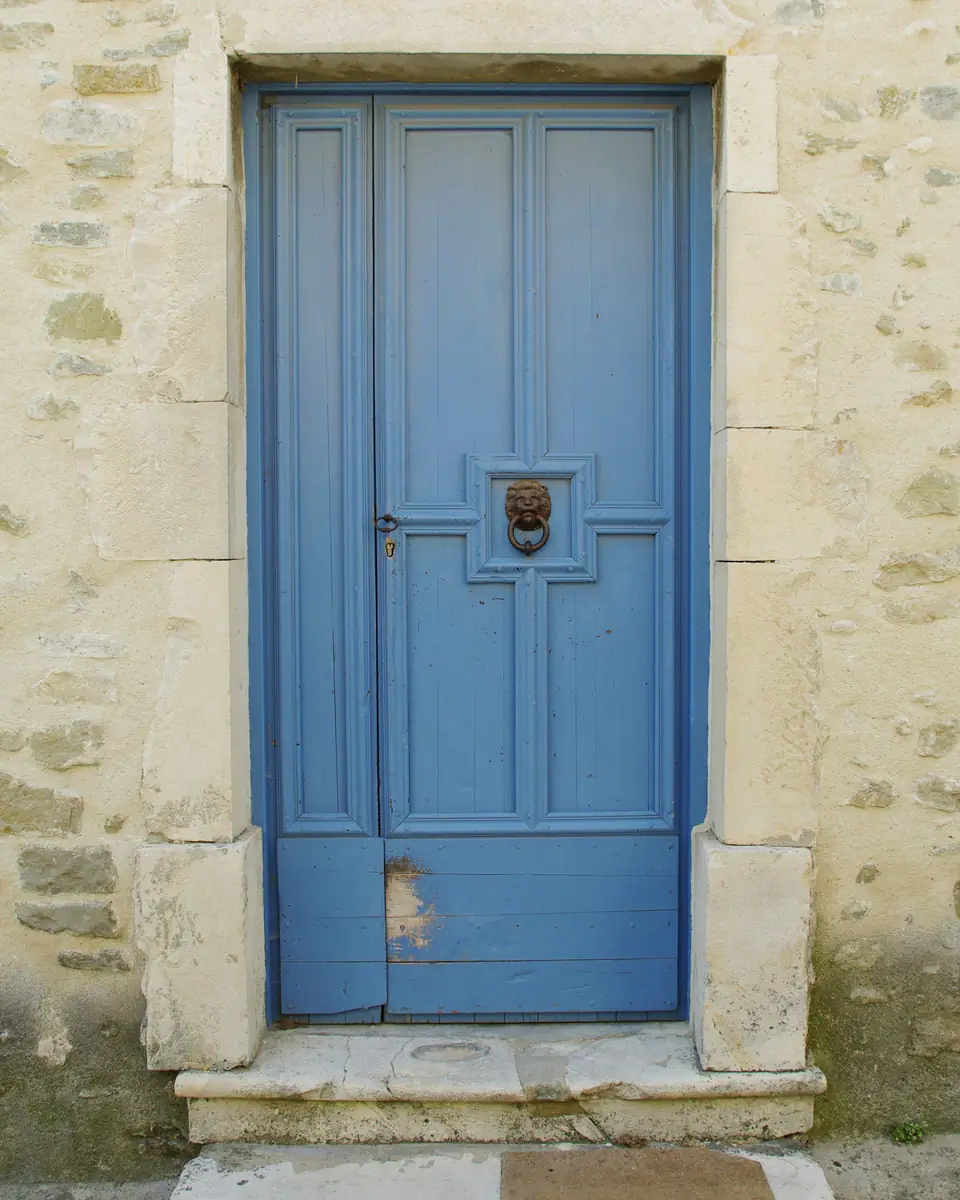 Puerta de madera restaurada y pintada de azul, con herrajes nuevos